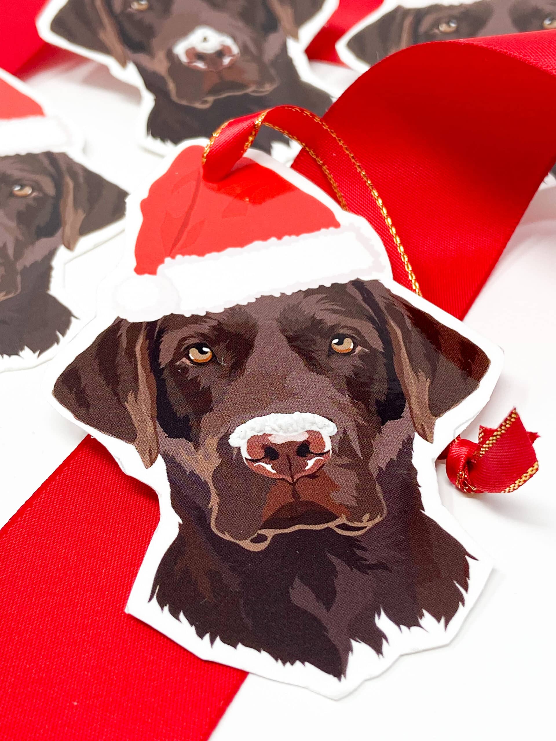 EXPLORING FRESH SNOW Brown Labrador Gift Tags - These beautiful gift tags feature the beloved chocolate Labrador retriever sporting a festive Santa hat and a light dusting of snow on his nose! The snow has 3D effect on the tags for added effect. Perfect for animal lovers of all kinds! ABOUT OUR TAGS These tags are made in the USA with heavyweight card stock and premium satin ribbon. Aside from printing, our gift tags are hand made and may have some slight inconsistencies between pieces, such as exact length of ribbon. These tags are made exclusively for Kenzies of London and are not found anywhere else. While they can be used as gift tags, they make wonderful paper ornaments and can be used for crafting and display purposes. BROWN LABRADOR GIFT TAGS SPECS Set of 6 Gift Tags Measures approximately 3x2.5" Printed on heavyweight card stock paper Tied with premium satin ribbon