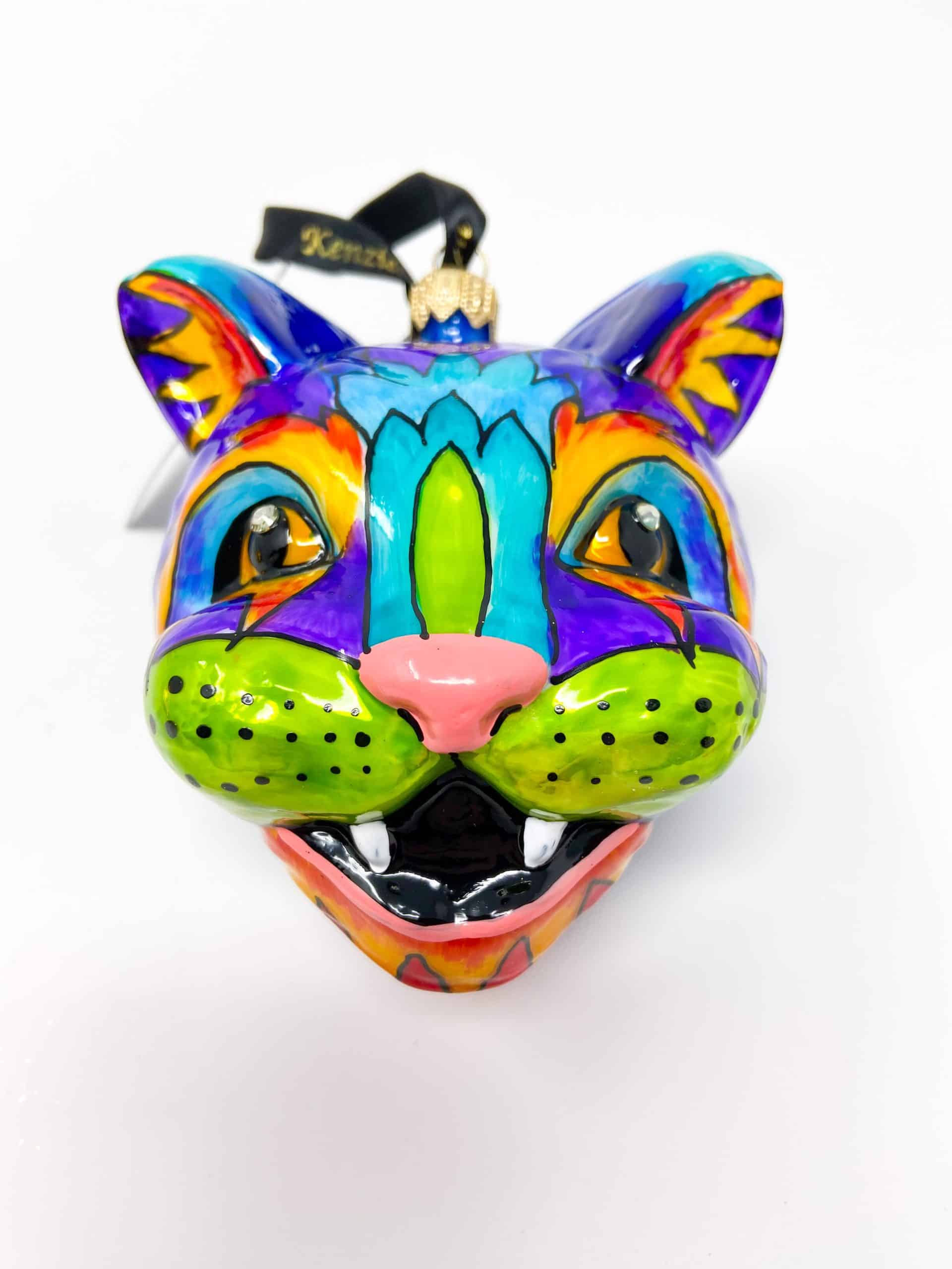 Add a pop of color and cultural flair to your holiday decor with our Cat Face Glass Ornament, painted in the vibrant style of Alibrejes art