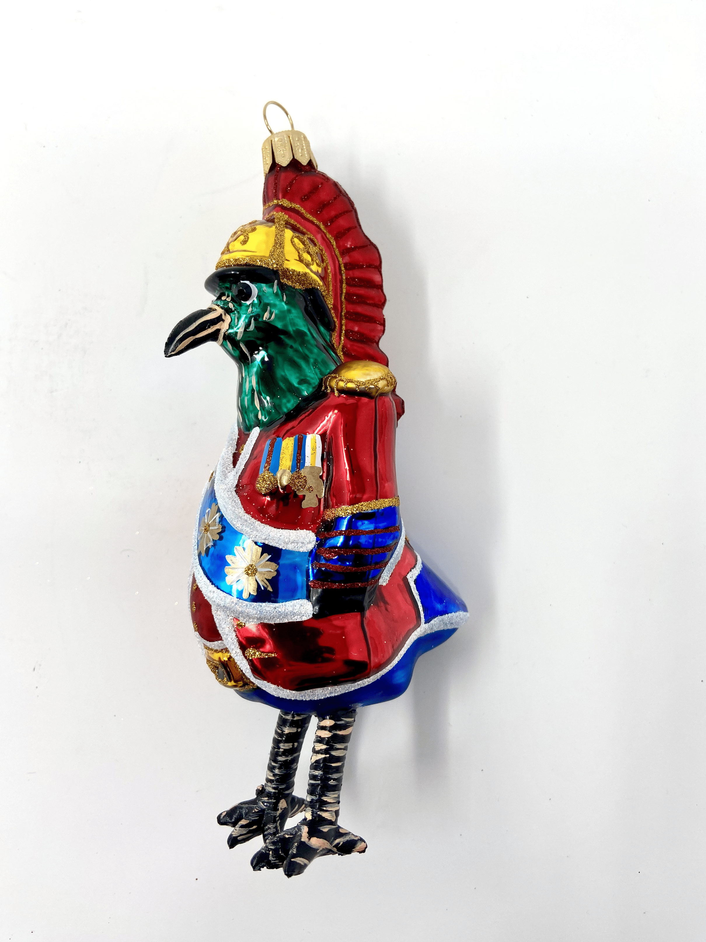 Blue bird dressed in a Buckingham Palace royal outfit with a blue sash and red coat. Polish glass christmas ornaments in saturated colors.