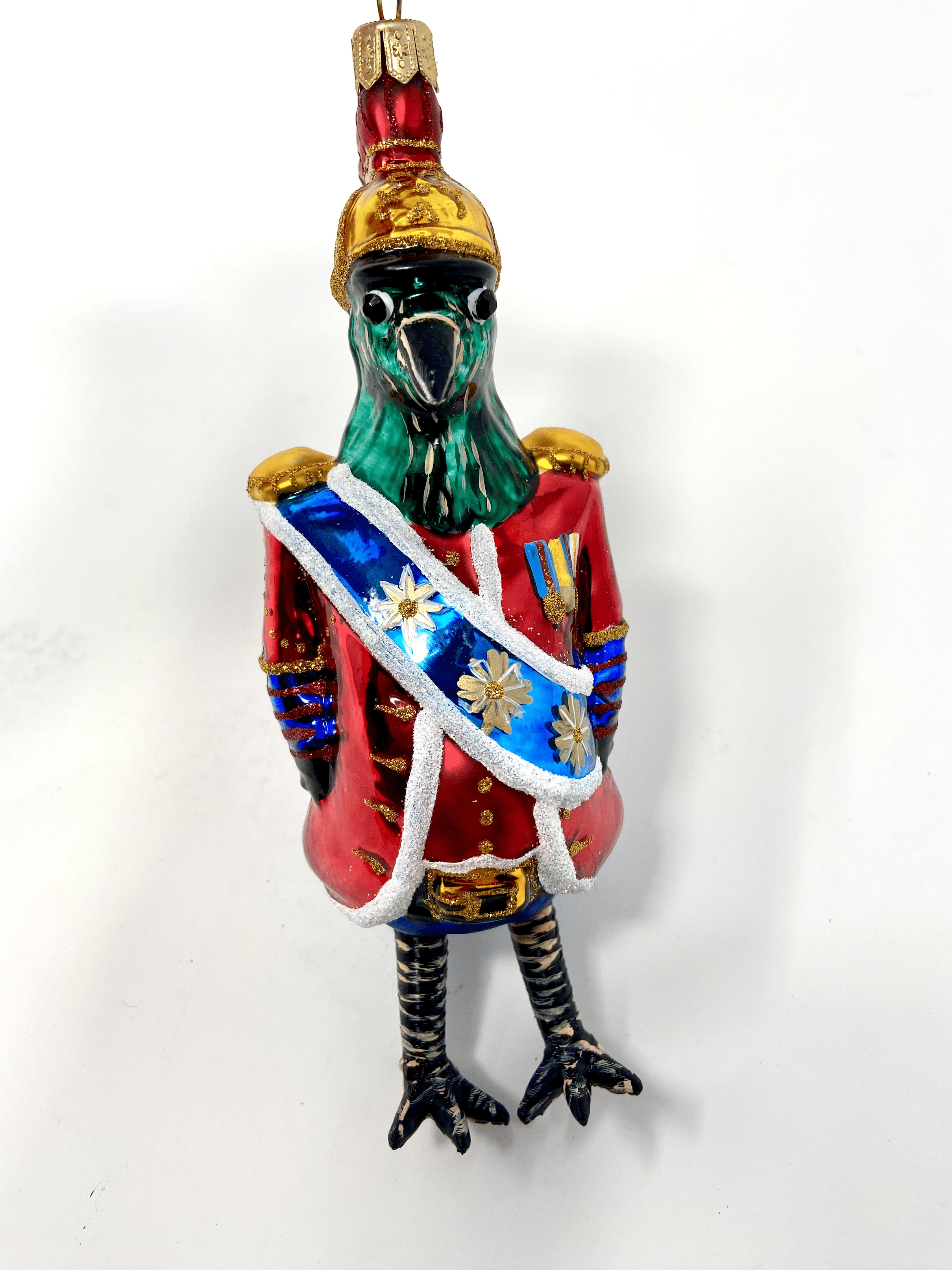 Blue bird dressed in a Buckingham Palace royal outfit with a blue sash and red coat. Polish glass christmas ornaments in saturated colors.