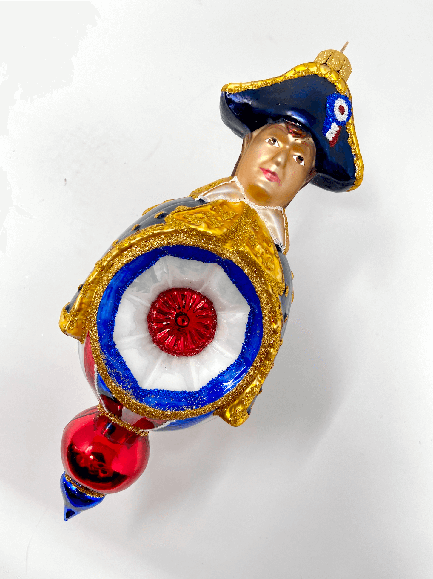 Beautiful Napoleon Bonaparte reflector ornament wearing a black cloak and colonial hat with red white and blue patriotic detailing. Polish glass christmas ornaments in saturated colors.