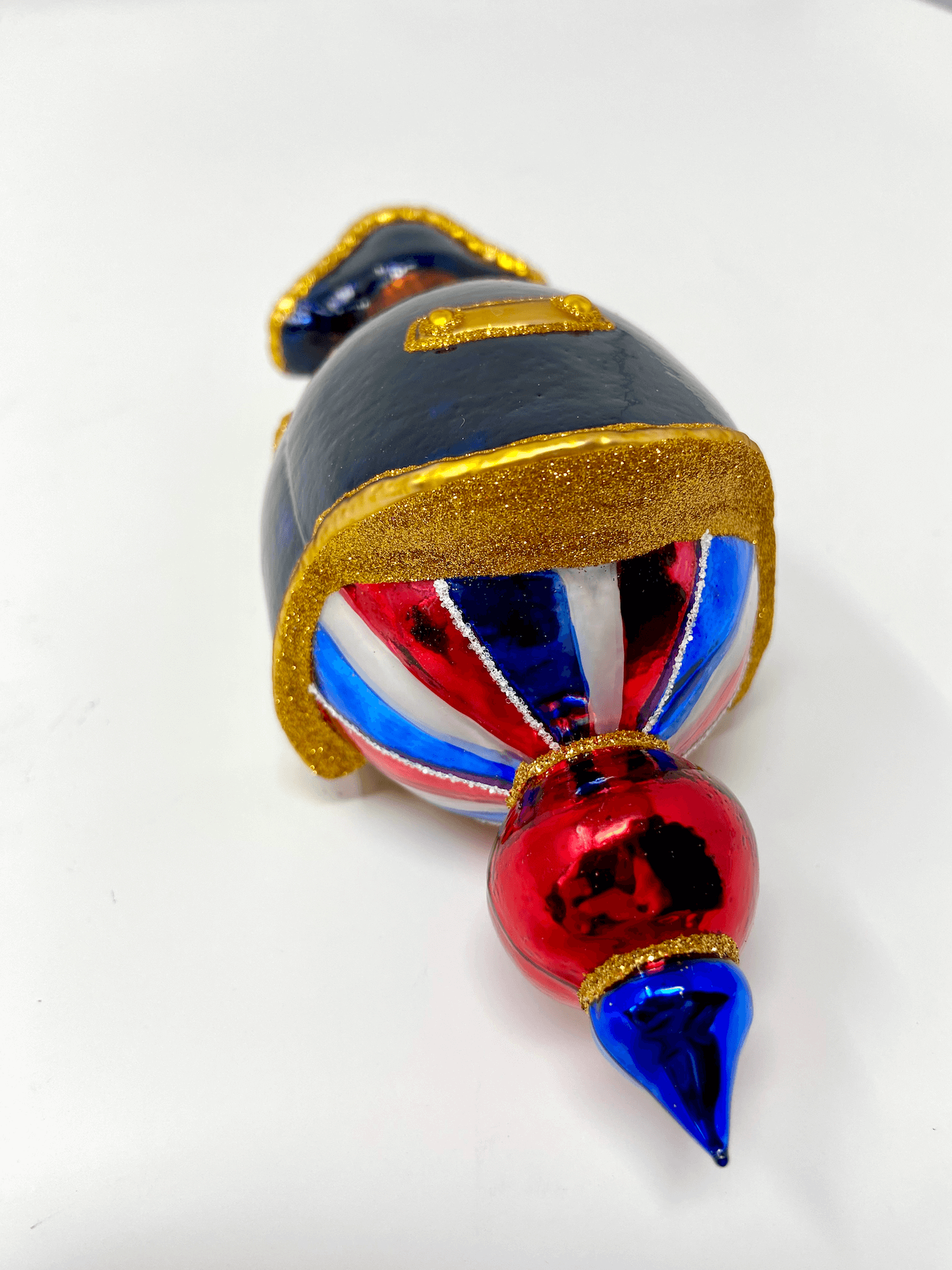 Beautiful Napoleon Bonaparte reflector ornament wearing a black cloak and colonial hat with red white and blue patriotic detailing. Polish glass christmas ornaments in saturated colors.