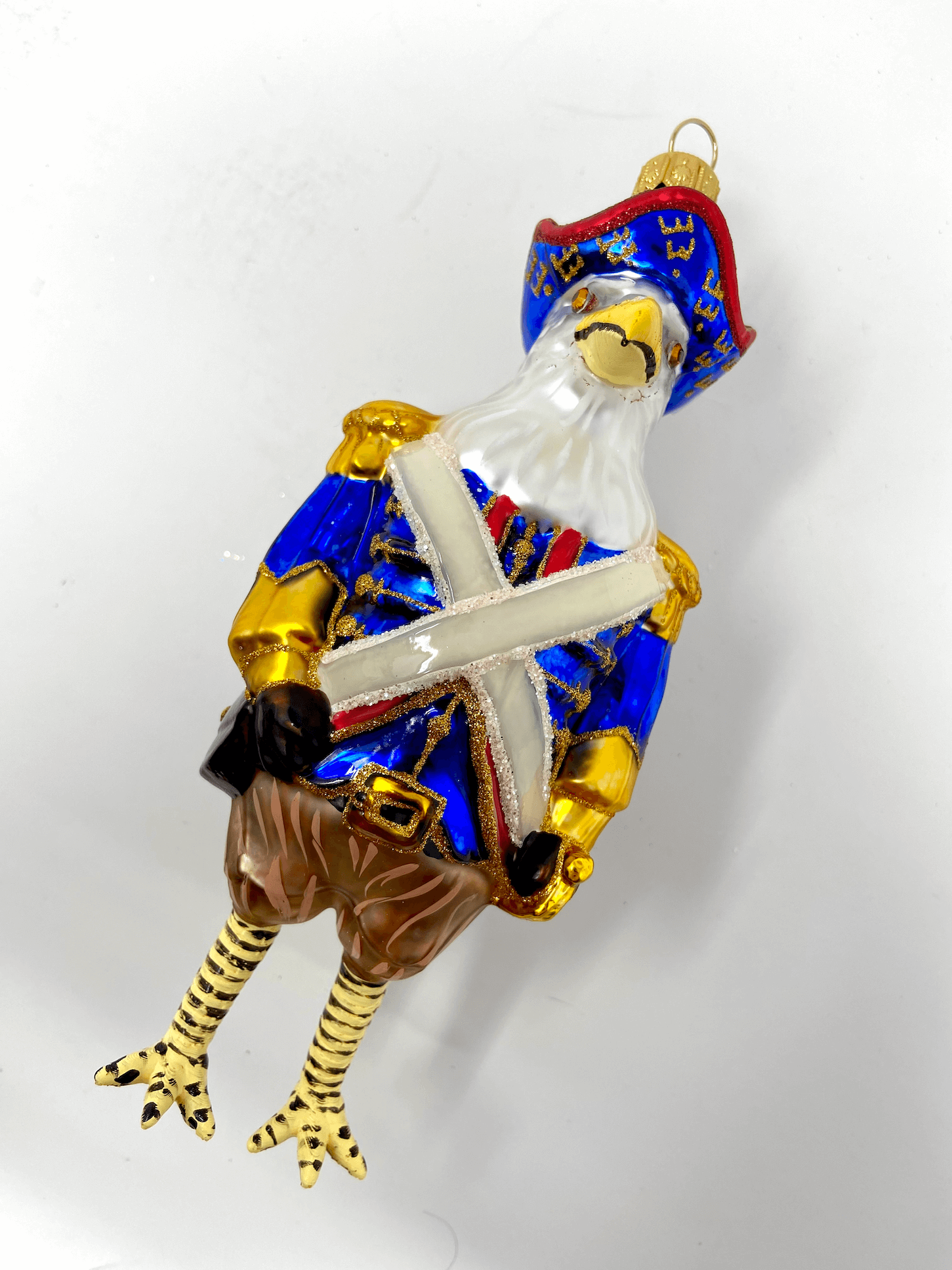 Beautiful and commanding american eagle dressed in a revolutionary war general's blue coat with gilded accents and white sash. Wearing a colonial blue had. Polish glass christmas ornaments in saturated colors.